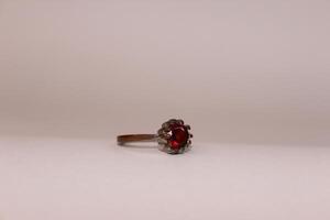 A red stone ring sitting on top of a white surface photo