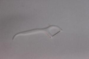 A white plastic toothpick laying on a white surface photo