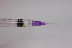 A syringe with a purple tip on a white background photo