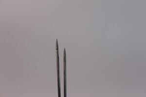 Two needles are sticking out of a white background photo