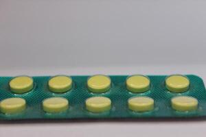 A pack of pills with green and yellow pills photo