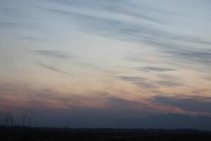 A plane flying over a field at dusk photo