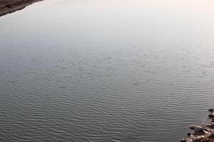 A man is standing on a rock next to a river photo