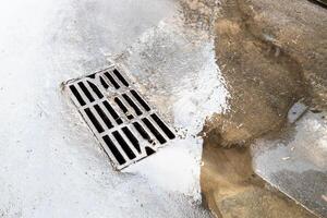 wet grate of street sewer and puddle on ubnan road photo