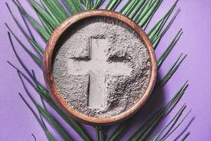 Bowl with cross imprint in gray ash on purple background. Ash Wednesday photo