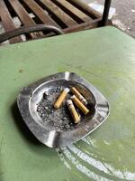 a cigarette is sitting on a table in a metal tray photo