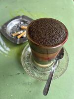 a cup of coffee with a cigarette sitting on top of it photo