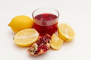 pomegranate and lemon next to a glass of pomegranate juice photo