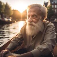 An older man with a beard and white hair is sitting in a boat on a river photo