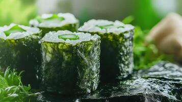 Healthy green sushi rolls made of seaweed, arranged on natural stone surface, with lush greenery in background photo
