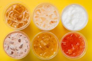 Takeaway glasses of summer drinks with ice. Lemonades and coctails top view photo