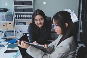 Two women in business attire sitting at a desk with a laptop photo