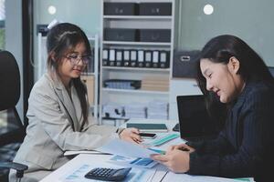 Two businesswomen in an office discussing paperwork photo