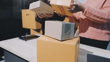 Two people are holding boxes and one is looking at them video