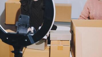 Two women are standing in front of boxes and a camera video