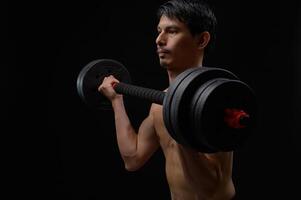 Strong Man Lifting Dumbbell in Dark Environment for Health and Fitness photo