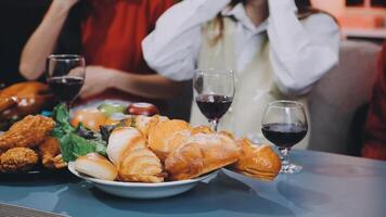A group of people sitting at a table with food and wine video