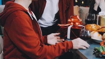 A man and woman are sitting at a table with a christmas tree video
