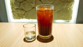 a glass of iced tea with simple syrup in a small glass, on a wooden table photo
