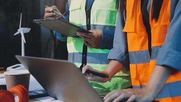 Two people in safety vests working on a laptop video