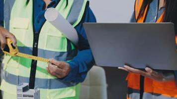Two construction workers are holding a laptop and measuring tape video