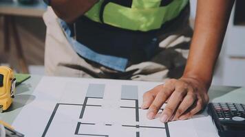 A person is working on a blueprint with a calculator and a pencil video