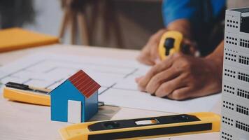 A person is working on a building project with a house model video