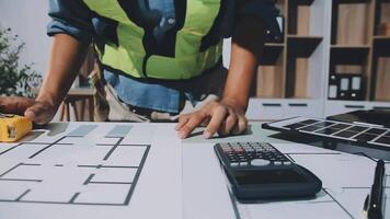 A man is working on a blueprint with a calculator and a calculator video