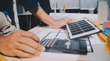 A person is using a calculator and a solar panel video