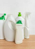 Cleaning products standing on wooden tabletop in front of white tiles wall photo
