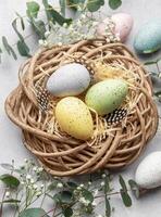 Easter eggs lying in nest surrounded by flowers and eucalyptus leaves photo