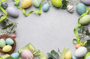 Easter eggs frame decorating a gray surface with ribbons and flowers photo
