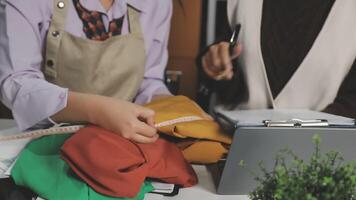 Two women are working on a laptop and a notebook video