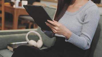 A woman sitting on a couch with a tablet computer video