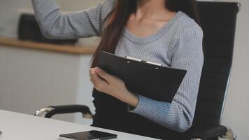 A woman is holding a clipboard while sitting at a desk video