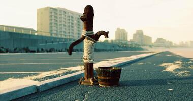 Old wooden post wrapped in rope near seaside with bucket at sunset video