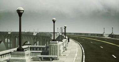 Lonely road with lampposts along the bridge under cloudy sky video
