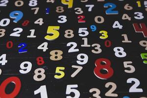 Colorful wooden numbers on blackboard background. Numbers written in wooden letters. photo