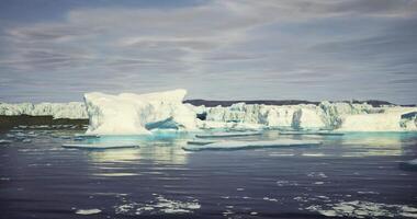 Icebergs floating in calm water under cloudy sky during daylight video