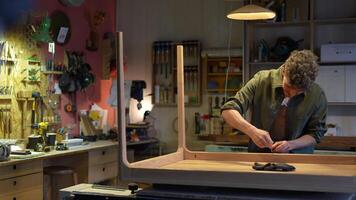 Focused man carpenter working with table, tightens table frame to tabletop with hexagonal wrench. video