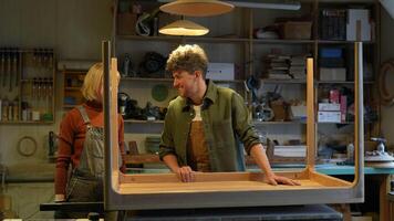 Cheerful carpenters spouses chatting laughing smiling moving table for further joint work. video