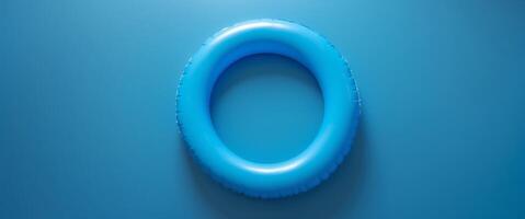 Bright blue inflatable pool ring resting on a solid blue background in a serene and calm setting. photo