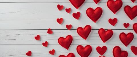 Red felt hearts arranged on a white wooden background creating a Valentine's Day themed border with copy space photo