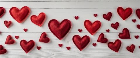 Red felt hearts arranged on a white wooden background creating a Valentine's Day themed border with copy space. photo