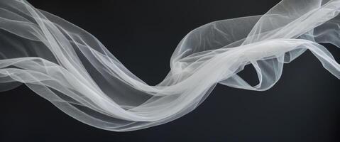 Elegant curves and shapes created by flowing delicate white tulle fabric on a black background. photo