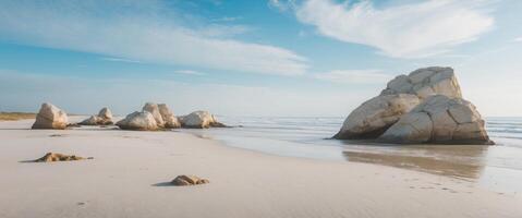 Scenic view of distinctive rock formations and pools on sandy beach under blue sky with clouds. photo