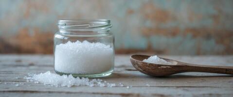 Salt in glass jar with wooden spoon on rustic background. photo