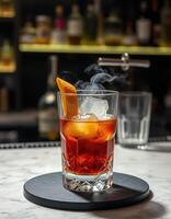 Craft cocktail garnished with orange peel and smoke served on a marble countertop during an evening gathering photo