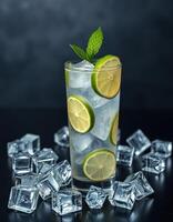 Refreshing citrus beverage served in a tall glass with fresh mint leaves and ice cubes on a dark background photo