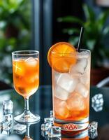 Refreshing cocktails served with ice and garnished with orange on a glass table surrounded by plants photo